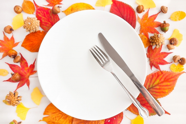 落ち葉の上のお皿とフォークとナイフ